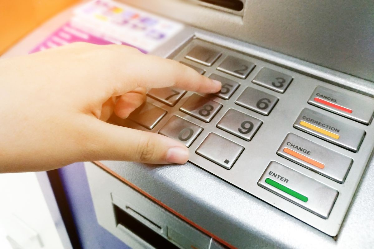 Woman hand entering PIN or password security code on ATM bank machine